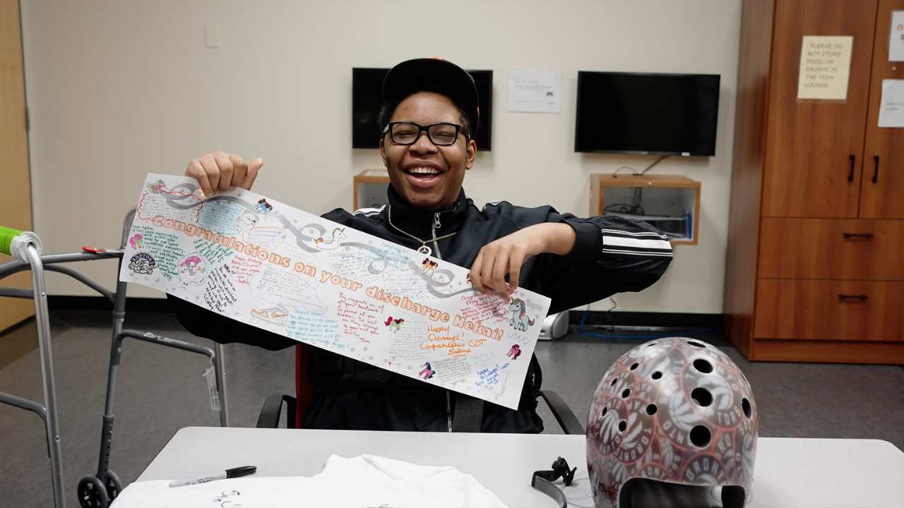 a man with glasses smiling and holind up a card